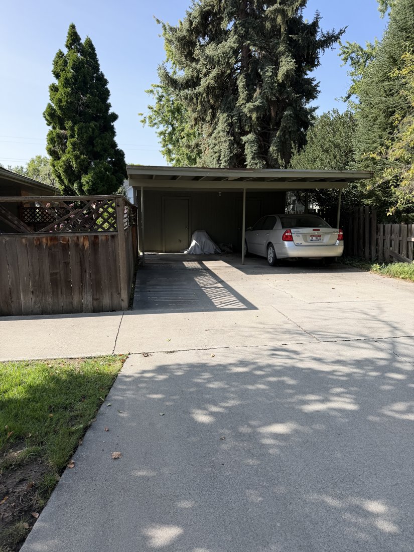 North and east sides, viewed from the southwest. Open covered parking bays and concrete driveway at one end of the brick group.