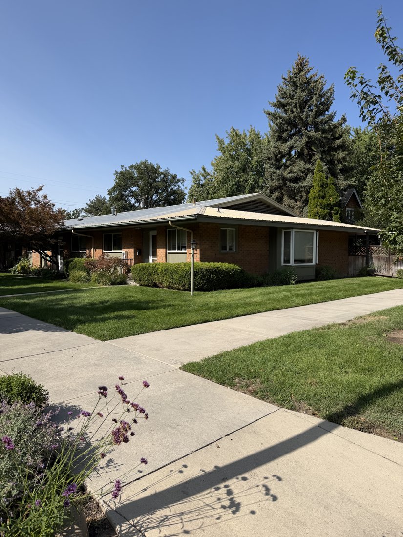 East side, viewed from the west. Oblique street view of the brick residential group with a projecting bay window and an entrance.