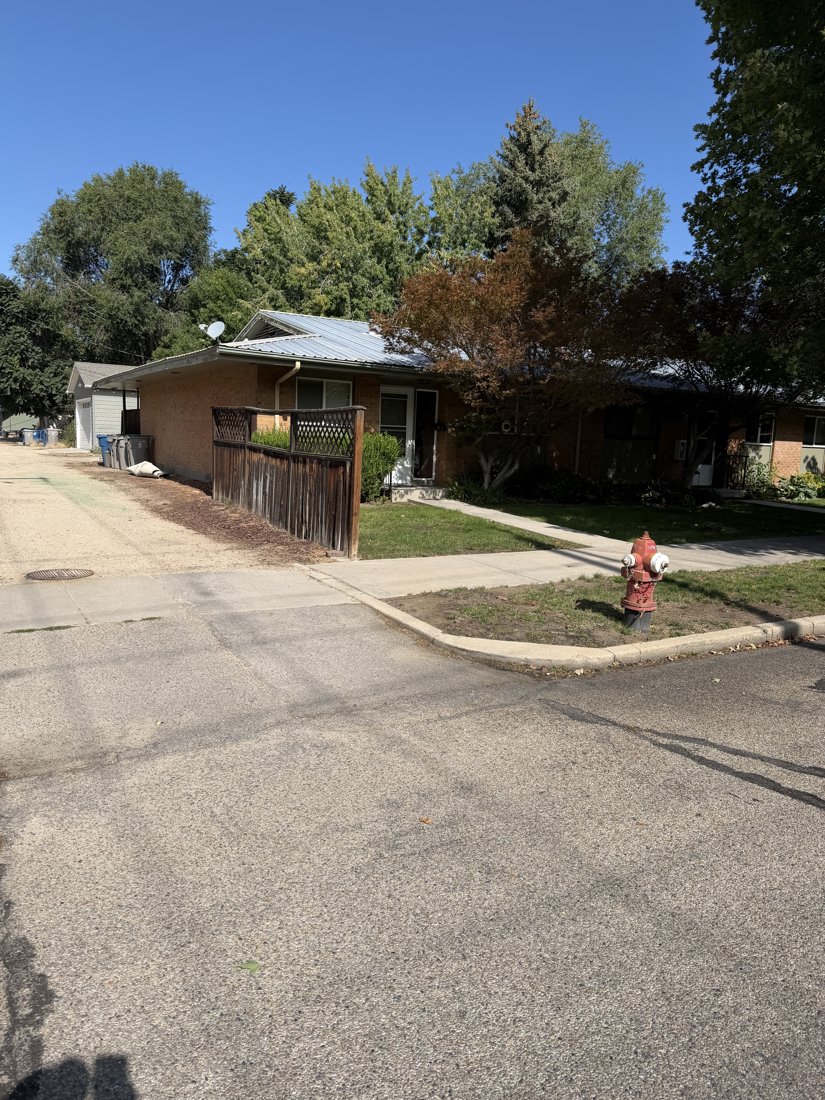 South and east sides, viewed from the northwest. Alley-end oblique with brick end wall, screened patio, and low metal roof.