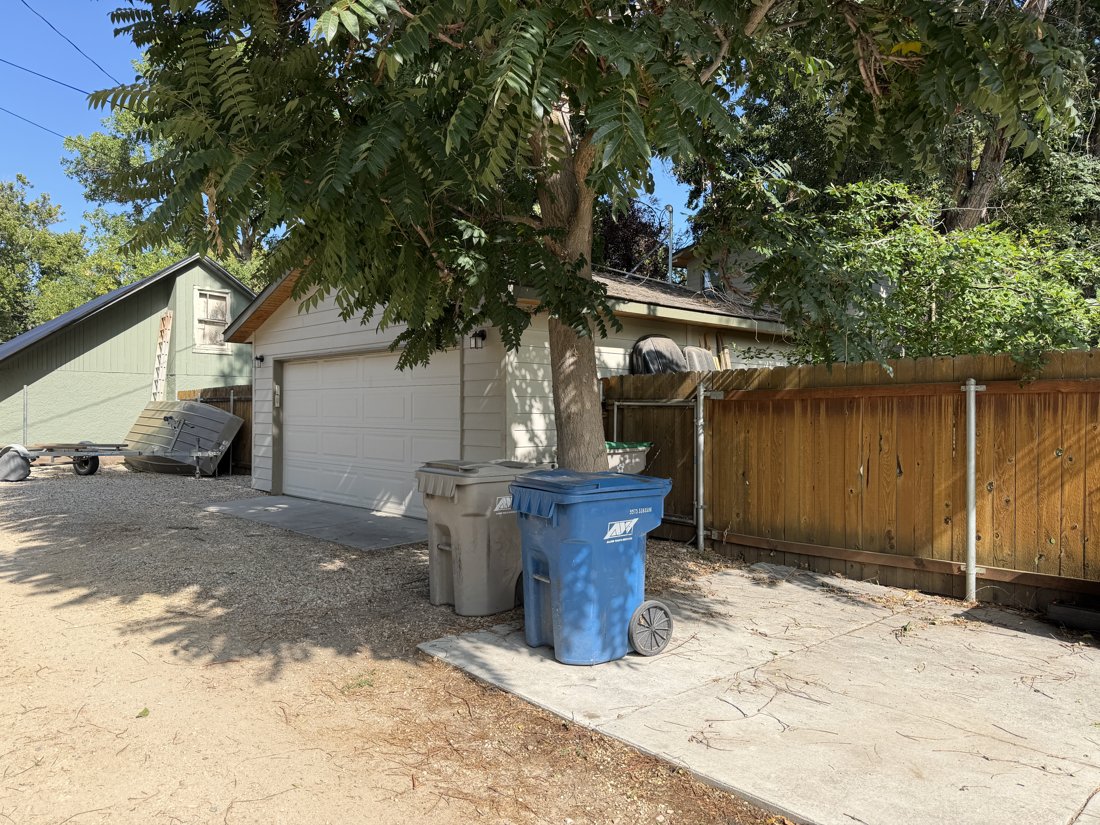 South and east sides, viewed from the northwest. Oblique view of the garage, sectional overhead door, and board fence.