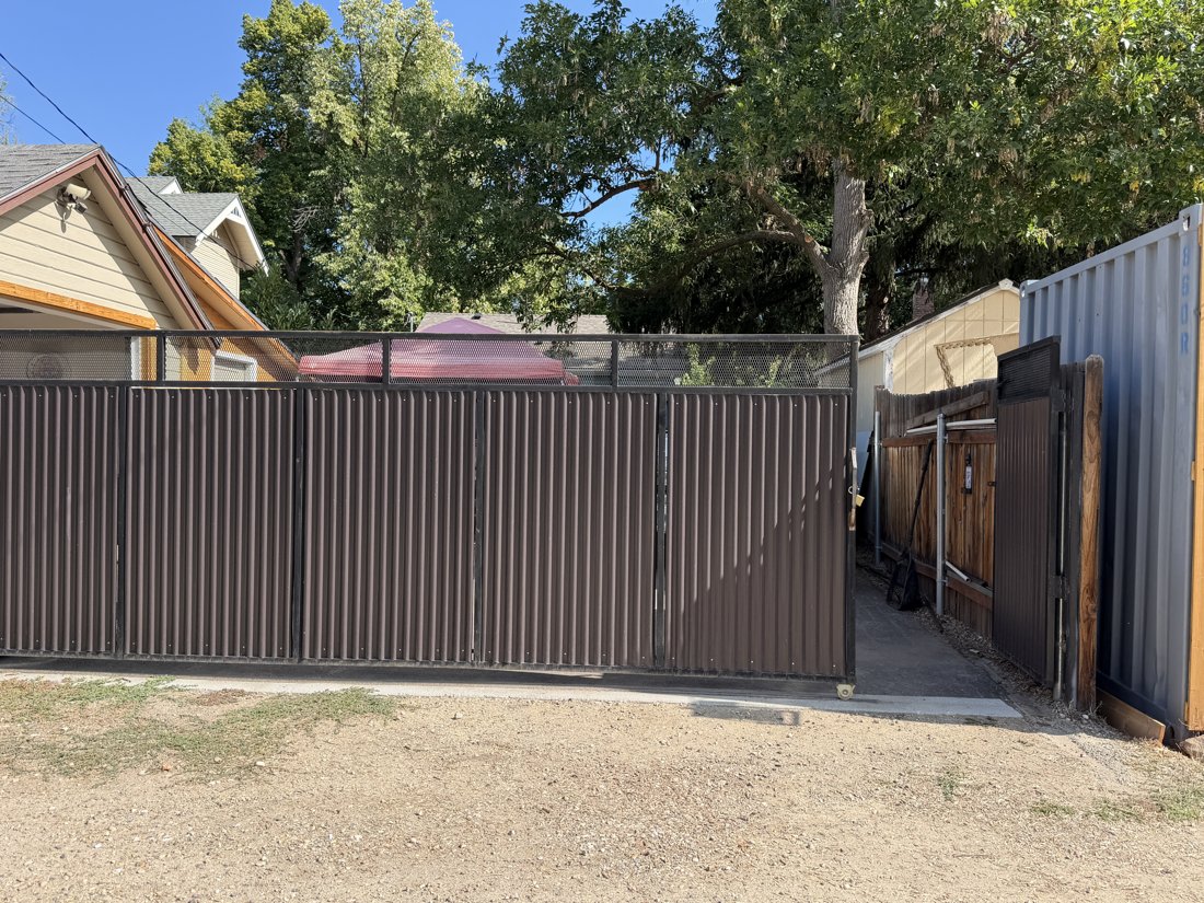 South side, viewed from the north. Sliding alley gate, fence, and rooflines within the rear property group; parcel connection requires confirmation.