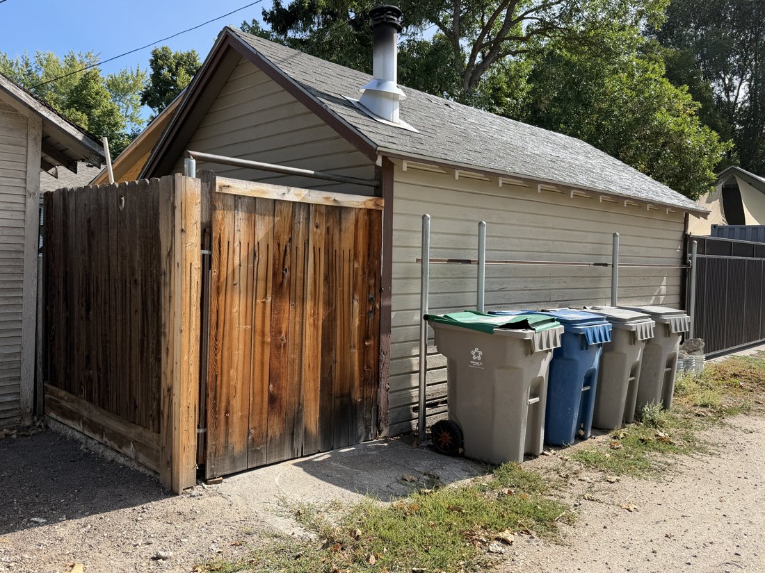South and west sides, viewed from the northeast. Opposite oblique of the gabled alley building, service gate, and bins; parcel connection requires confirmation.