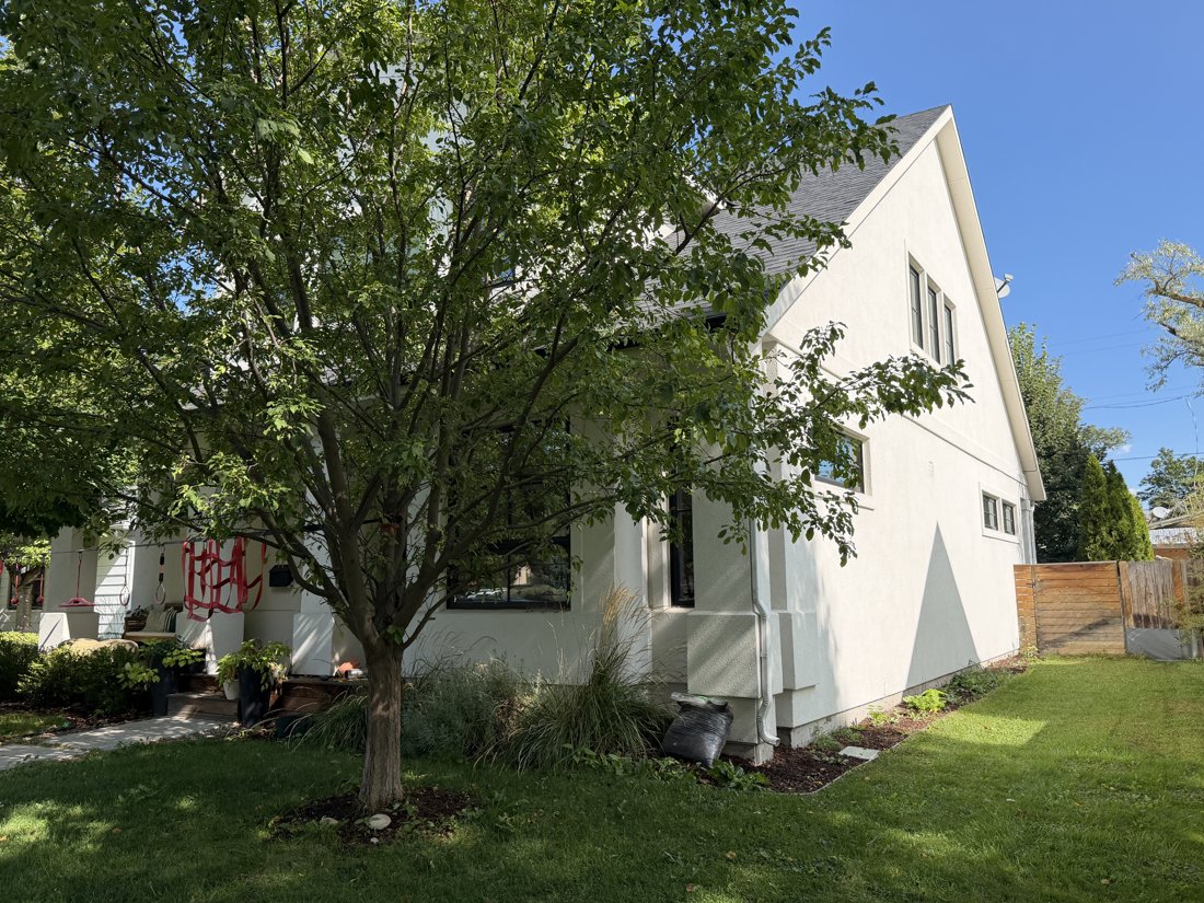 South side, viewed from the north. Opposite oblique of the stucco house with tall side wall and front porch.