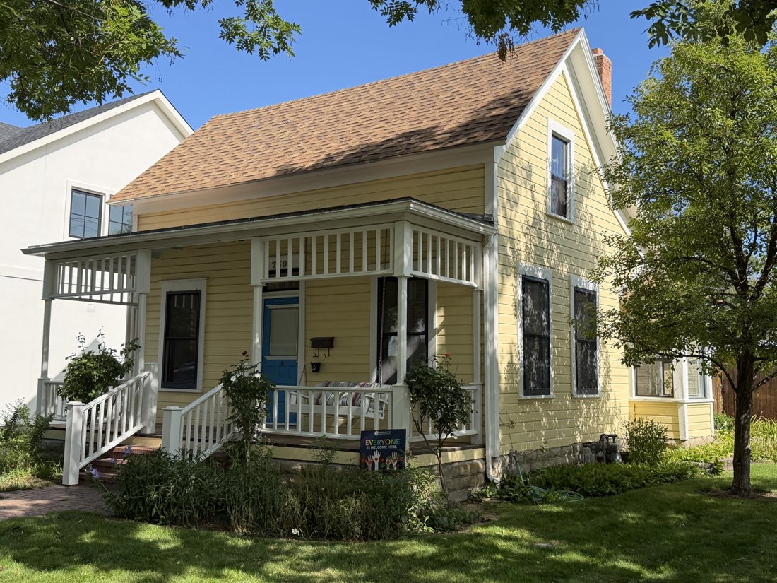 South side, viewed from the north. Opposite front oblique showing the side gable, upper windows, and porch return.