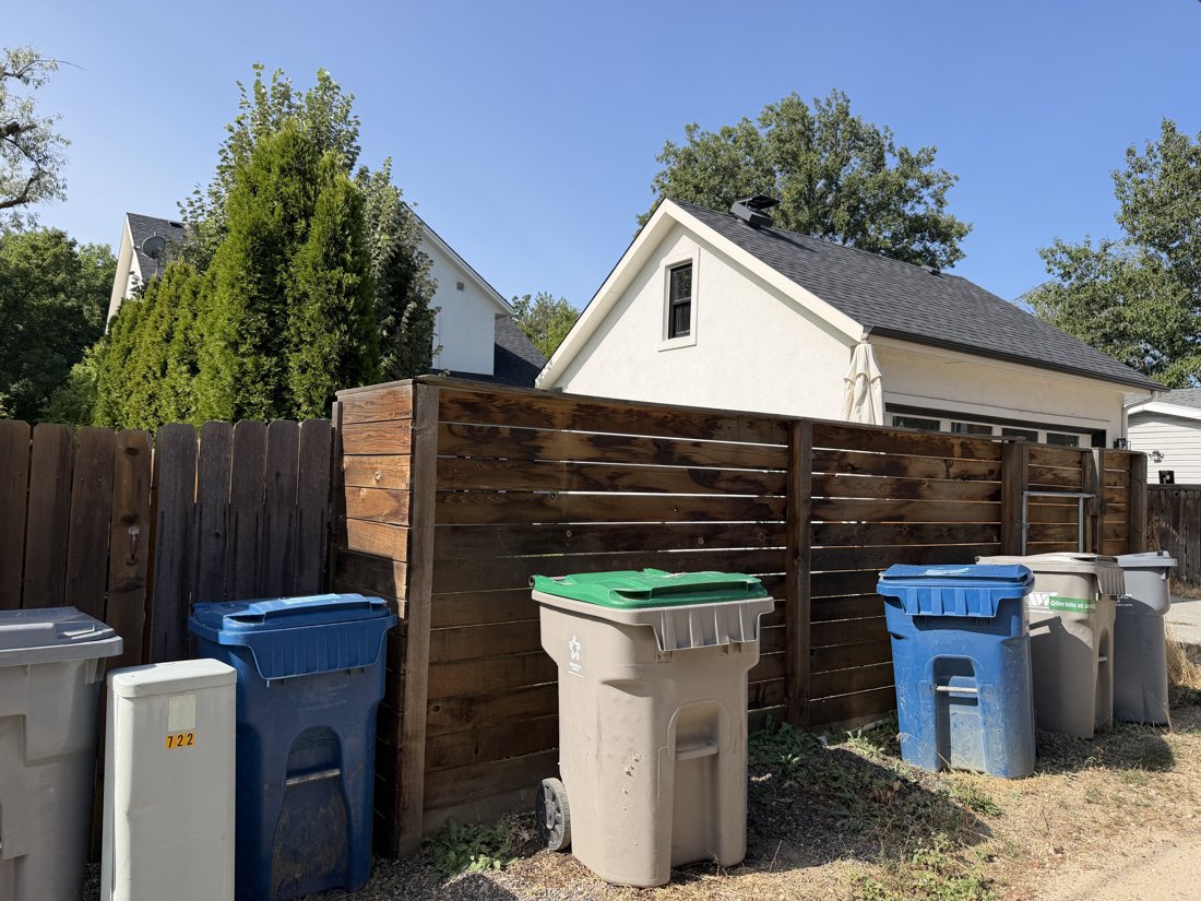 North and east sides, viewed from the southwest. Fenced yard and gabled garage with the house beyond.