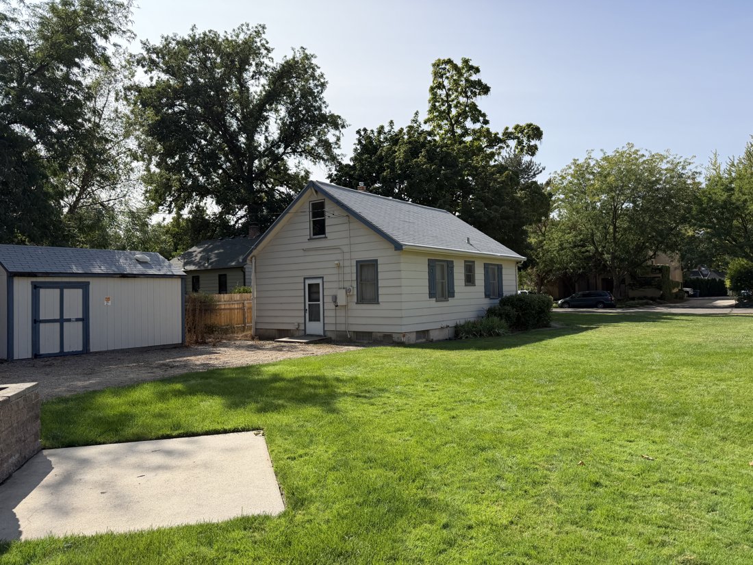 North side, viewed from the south. Rear and side oblique of the house, lawn, and small shed.