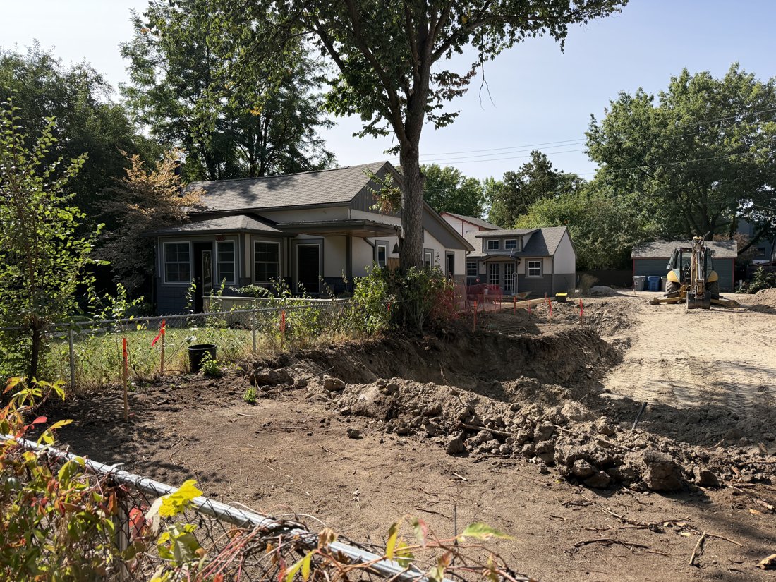 Not evident side, viewed from the north. Open excavation, temporary fencing, and adjacent building context.